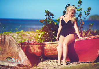 plus size young woman sitting on the boat on sunny beach