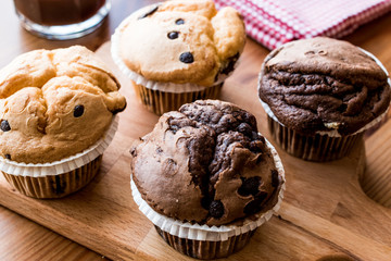 Chocolate and Vanilla Muffins with coffee on wooden surface.