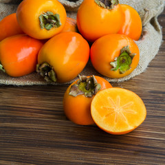 Close up of fresh organic persimmon fruit cut in half on rustic wood background. Concept for healthy food, vegan or raw diet. Copy space.