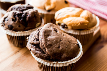 Chocolate and Vanilla Muffins with coffee on wooden surface.