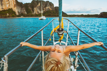 Vintage style child portrait. Happy baby girl on board of sailing yacht have fun discovering islands in tropical sea on summer coastal cruise. Travel adventure, yachting with kids on family vacation.
