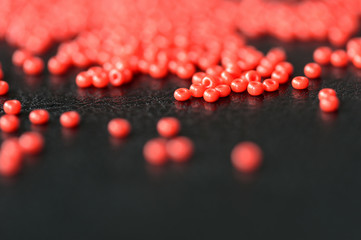 Red seed beads scattered on a dark background