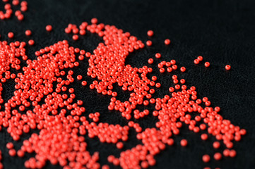 Red seed beads scattered on a dark background