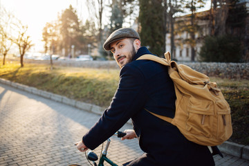 Bearded man with backpack riding bicycle 