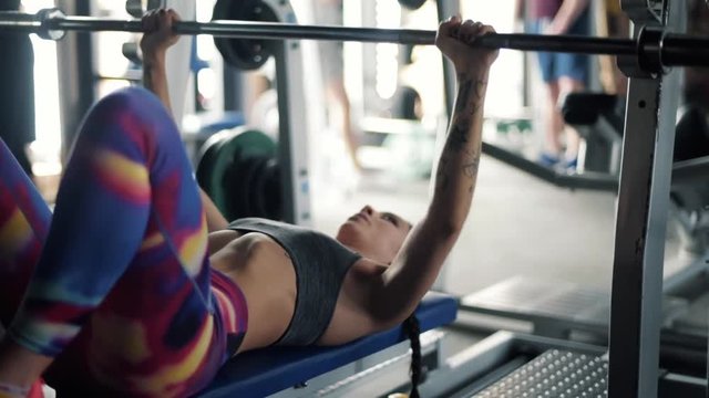 Young woman doing bench presses with weights 