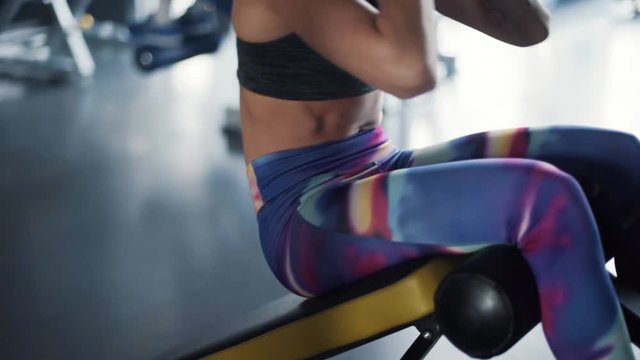 Woman doing sit ups on bench for train her abdominal 