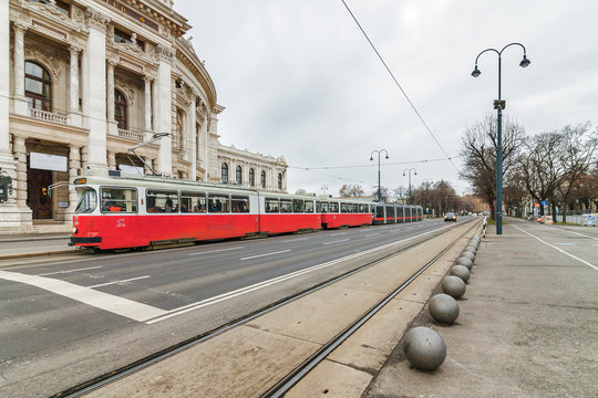 Cloudy view of Wiener Ringstrasse with historic Burgtheater (Imperial Court Theatre) and traditional red electric tram in Vienna, Austria