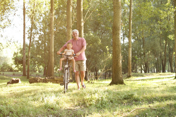 Senior man with granddaughter in bicycle basket.