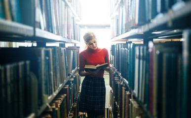 Reading a book in library - obrazy, fototapety, plakaty