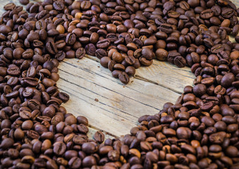 Heart of coffee. Roasted Coffee beans on natural wooden background