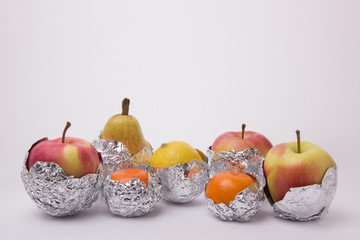Juicy fruit, yellow pear, apple, lemon and orange tangerines wrapped in foil on a white background