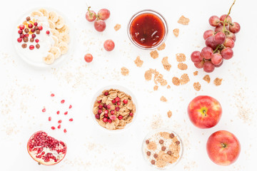 Healthy breakfast with yogurt, muesli, fresh fruits and berries, cereal, nuts on white background. Flat lay, top view.