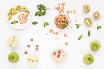 Healthy breakfast with yogurt, muesli, fresh green fruits, cereal, nuts on white background. Flat lay, top view.