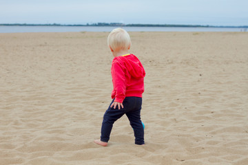 Blond baby walking on the beach