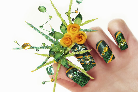Nail design with acrylic yellow roses and leaves hand-female hand with sequins,rhinestones,beads on a white background closeup.