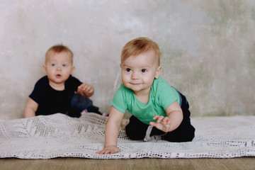 Fototapeta premium Two brother twins sitting. Two little kid boys watching at camera. Twins sitting together. People, children, friends and friendship concept