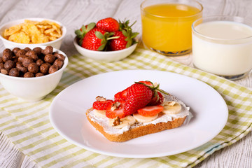 breakfast: Fresh toast with strawberry, banana and nuts, cornflakes, orange juice, milk
