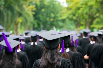 Back of graduates during commencement at university. Close up at graduate cap.