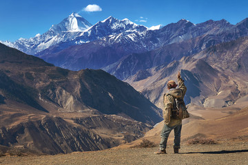 Tibetan local man standing and waving his hand to the Dhaulagiri mountain peak in Himalayas, Nepal