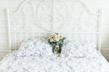 Wedding bouquet with white and pink tulips and pink small roses on a bridal bed with black and white bedclothes on a brick background