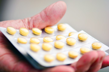 Old woman holding pills in her hand. Elderly female hand with pills or pharmaceutical meds.