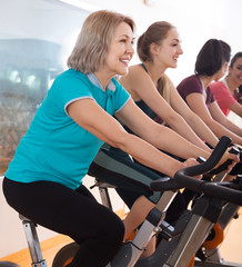 Fototapeta na wymiar Active females of different age training on exercise bikes