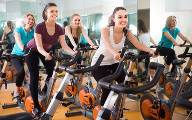 several women of different age training on exercise bikes