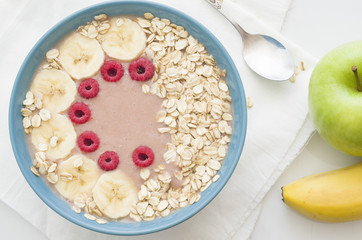 Smoothies in a plate with oatmeal, banana and raspberries