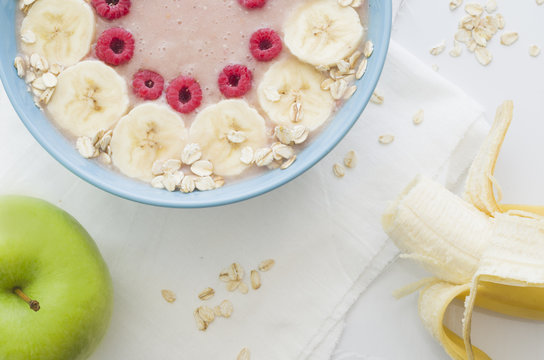 Smoothies in a plate with oatmeal, banana and raspberries