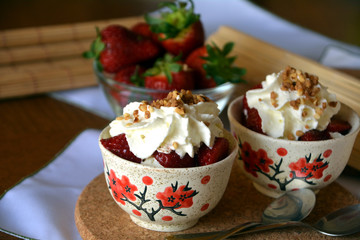 Refreshing snack chopped strawberries and whipped cream on a nice bowl.