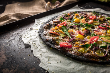Italian pizza with black dough and seafood on a baking tray from the oven