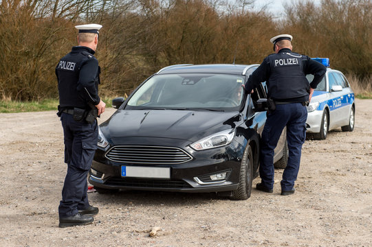 Polizisten kontrollieren ein Fahrzeug auf einem Parkplatz