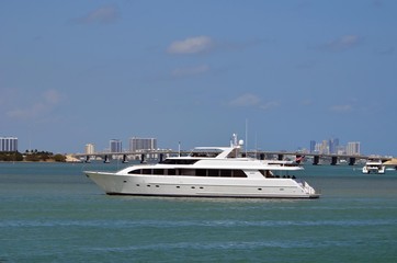 Fototapeta na wymiar Luxurious white motor yacht at idle on the florida intra-coastal waterway with a Julia Tuttle Causeway bridge in the background.