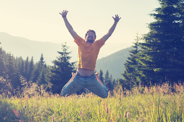 Joyful man jumping and having fun on alpine meadow