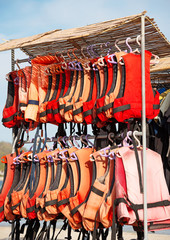Many life jackets on the beach.