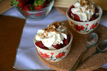 Refreshing snack chopped strawberries and whipped cream on a nice bowl.
