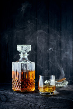 Glass of whiskey and carafe on a black wooden table