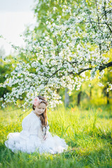 girl with a goat sitting in the grass in a lush apple orchard