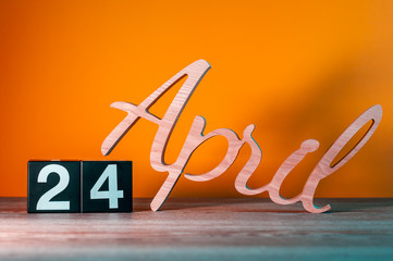 April 24th. Day 24 of month, daily wooden calendar on table with orange background. Spring time...