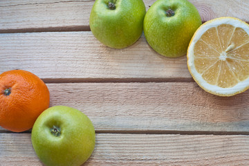 Apples, lemon and mandarin on a wooden background