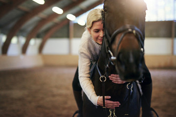 Blonde female sitting astride and hugging horse