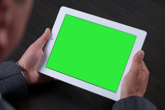 Businessman in office holding tablet computer with green screen
