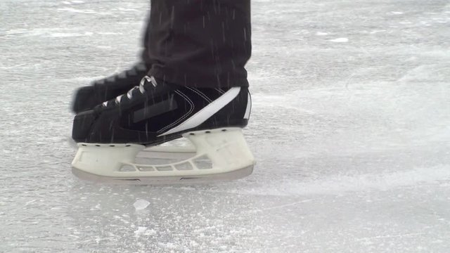 Mens Legs In Black Hockey Skates In A Slow Motion With Ice Spray