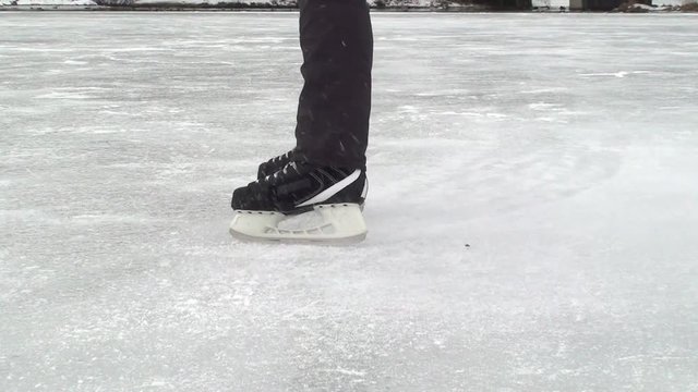 Mens legs in black hockey skates in running speed with ice spray
