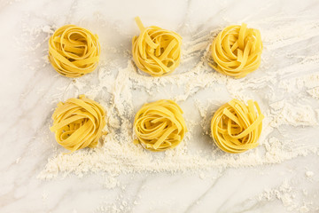 Overhead photo of pasta nests on white marble