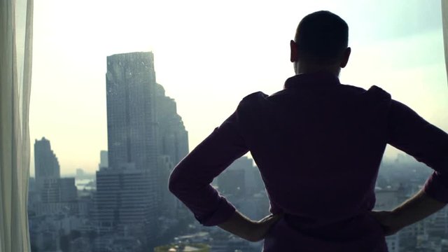Young man looking bt the window at the city, super slow motion 
