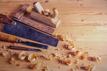 Carpentry tools concept, vintage equipment for working with wood. planer, saw and chisel on wooden table with shavings 