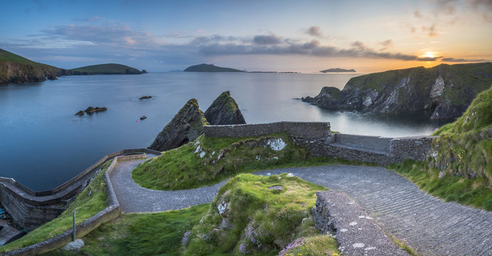 Dunquin pier (D&Atilde;&ordm;n Chaoin), Dingle peninsula, County Kerry, Munster province, Ireland, Europe. Panoramic view of the trail at sunset.