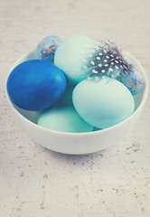 Plate with painted blue eggs on wooden table desktop, retro toned