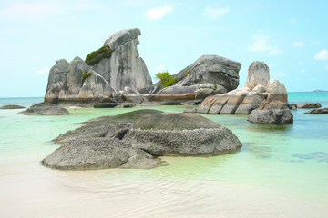 Natural rock formation in the sea and on a white sand beach in Belitung Island in the afternoon, Indonesia.